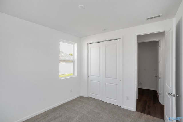 unfurnished bedroom featuring light colored carpet and a closet