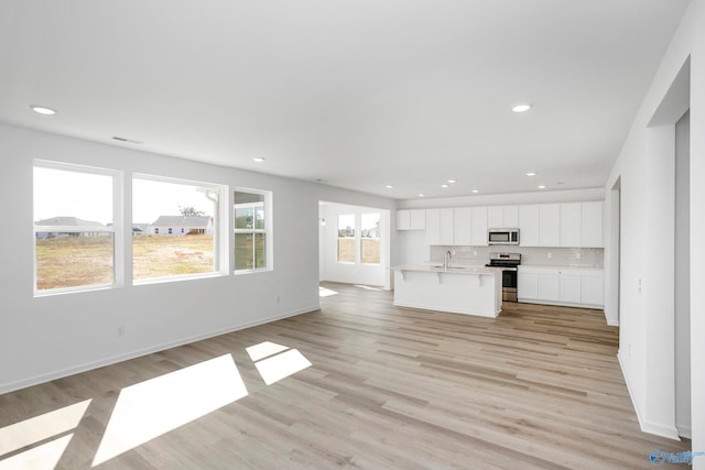 unfurnished living room featuring sink and light hardwood / wood-style floors