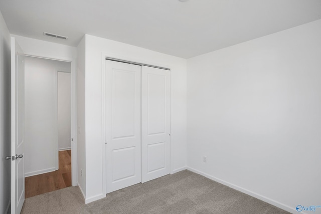 unfurnished bedroom with light colored carpet and a closet