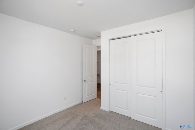 unfurnished bedroom with light carpet and a closet