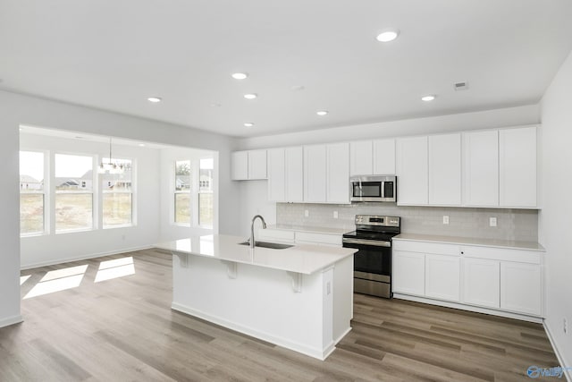 kitchen featuring sink, white cabinets, a kitchen island with sink, light hardwood / wood-style floors, and stainless steel appliances