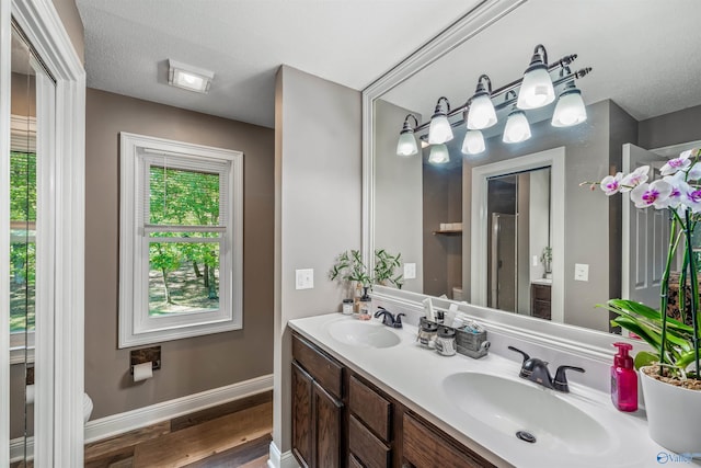 bathroom with hardwood / wood-style floors, toilet, vanity, and a textured ceiling