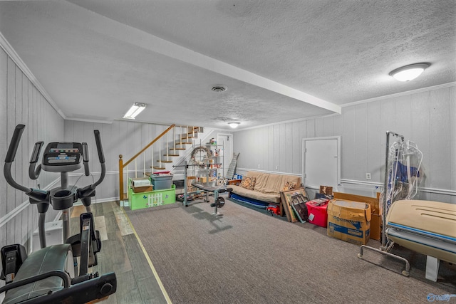 workout area featuring crown molding, hardwood / wood-style floors, wooden walls, and a textured ceiling