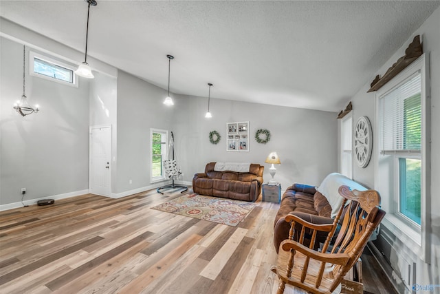 living room with high vaulted ceiling, wood-type flooring, and a textured ceiling