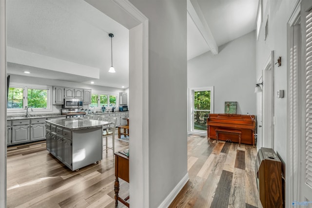 kitchen featuring gray cabinets, appliances with stainless steel finishes, a kitchen island, and a wealth of natural light