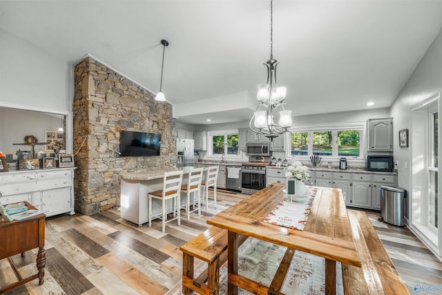 kitchen featuring a breakfast bar, gray cabinetry, a chandelier, light hardwood / wood-style flooring, and appliances with stainless steel finishes