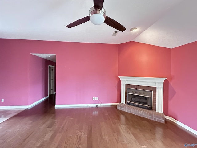 203 Lincoln Ave, Muscle Shoals, AL 35661 - unfurnished living room with a ceiling fan, vaulted ceiling, wood finished floors, a brick fireplace, and baseboards