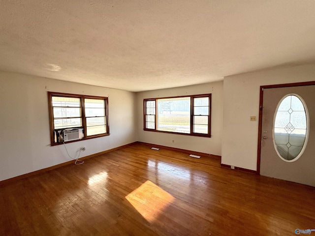 entryway with cooling unit, wood finished floors, baseboards, and a textured ceiling