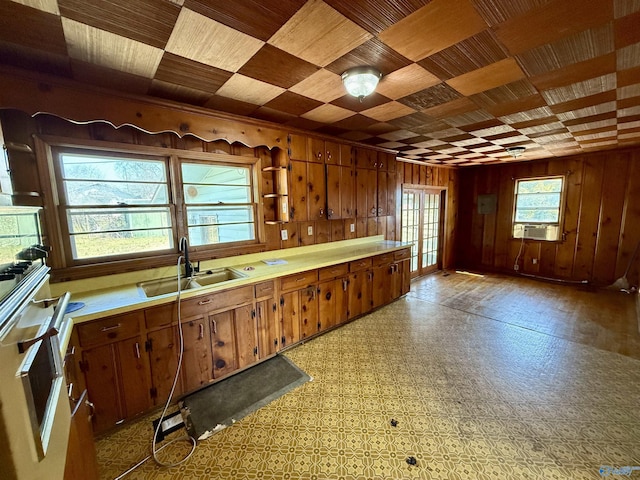 kitchen featuring wood walls, wood ceiling, light countertops, white oven, and a sink