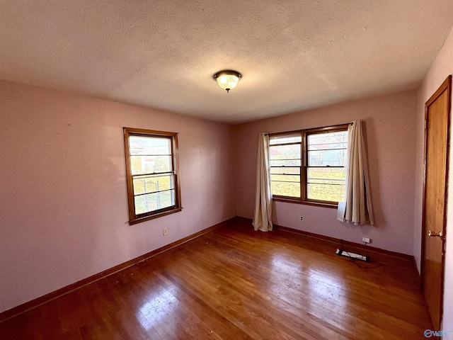 empty room featuring wood finished floors, baseboards, and a textured ceiling