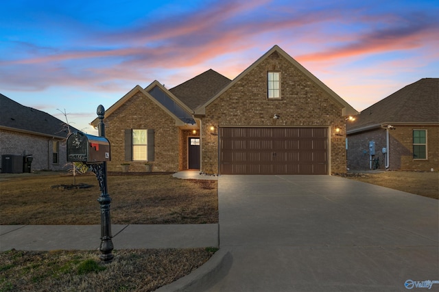 traditional-style home with an attached garage, a yard, concrete driveway, central air condition unit, and brick siding