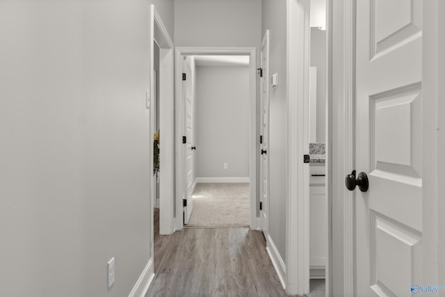 corridor with light wood finished floors and baseboards