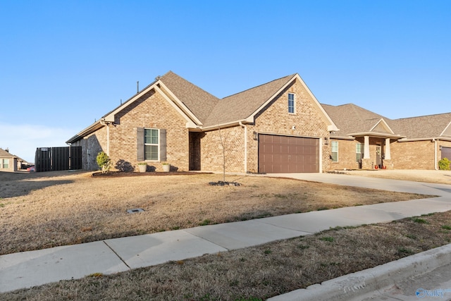 view of front facade featuring an attached garage, brick siding, driveway, and roof with shingles