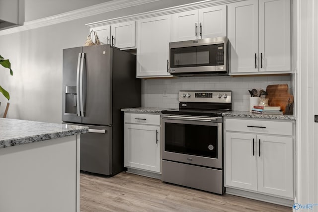 kitchen with ornamental molding, tasteful backsplash, white cabinetry, light wood-style floors, and appliances with stainless steel finishes