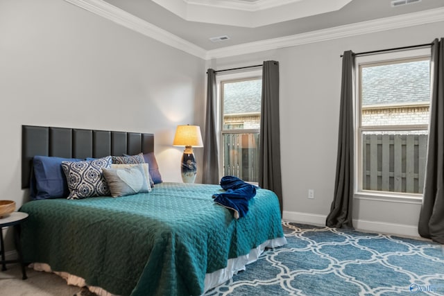 carpeted bedroom featuring visible vents, a raised ceiling, crown molding, and baseboards