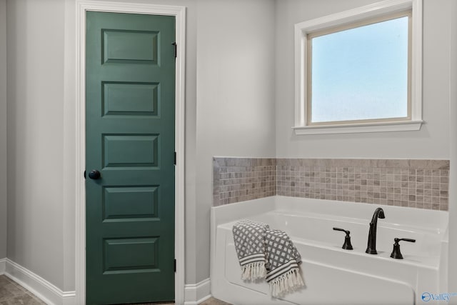 bathroom featuring a bath and baseboards