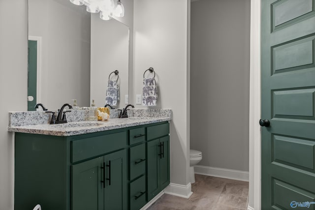 full bath with double vanity, toilet, baseboards, and a sink