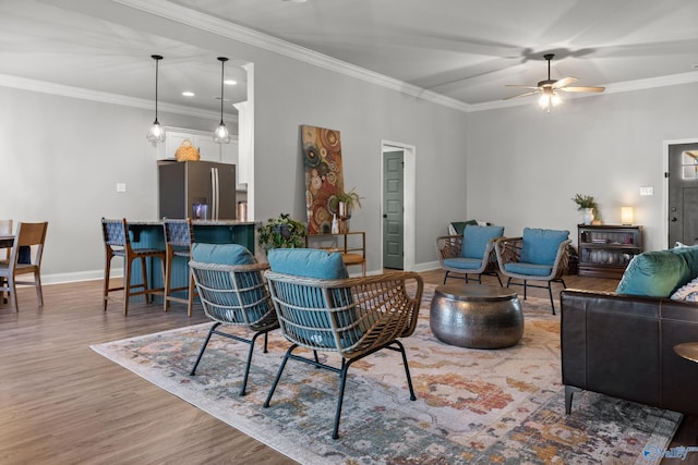 living area featuring ceiling fan, wood finished floors, baseboards, and ornamental molding