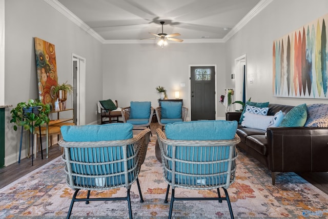 living area with ceiling fan, wood finished floors, baseboards, and ornamental molding