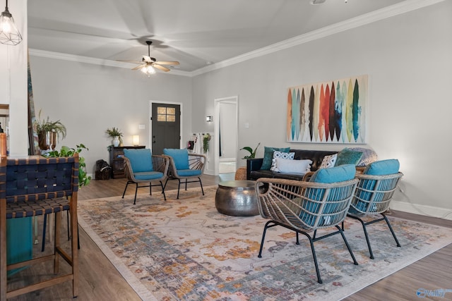 living area with crown molding, wood finished floors, baseboards, and ceiling fan