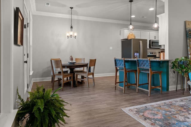 dining area featuring visible vents, crown molding, baseboards, an inviting chandelier, and wood finished floors