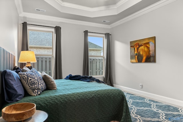 bedroom with a tray ceiling, baseboards, visible vents, and ornamental molding