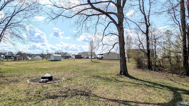 view of yard featuring a fire pit, a storage shed, and an outdoor structure