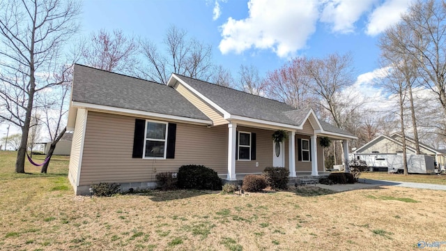 view of front facade featuring crawl space, covered porch, a shingled roof, and a front yard