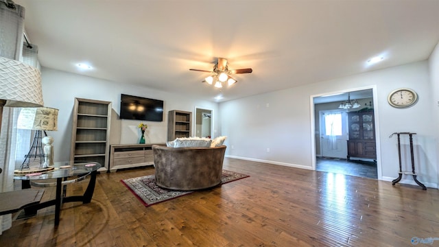 living room featuring dark wood finished floors, baseboards, and ceiling fan