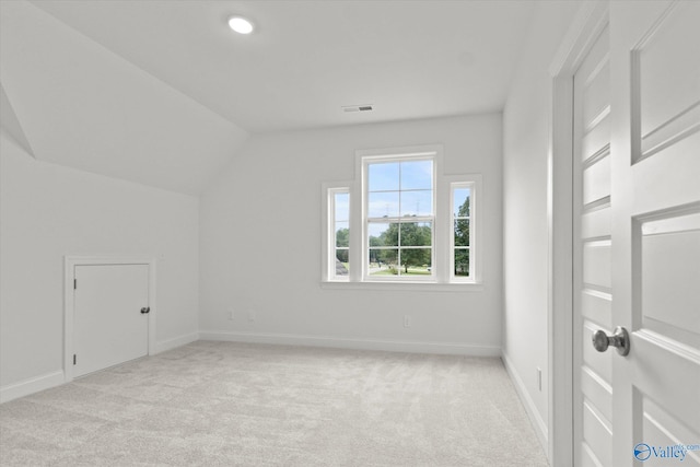 additional living space featuring vaulted ceiling and light colored carpet