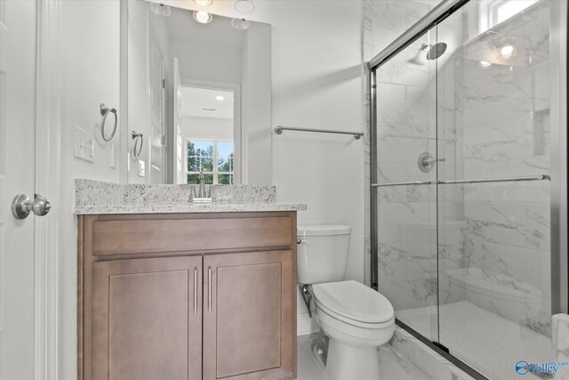 bathroom featuring vanity, a shower with shower door, and toilet