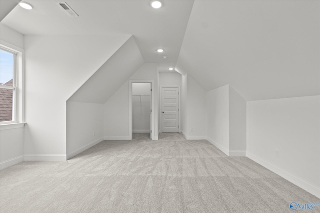 bonus room with lofted ceiling and light colored carpet