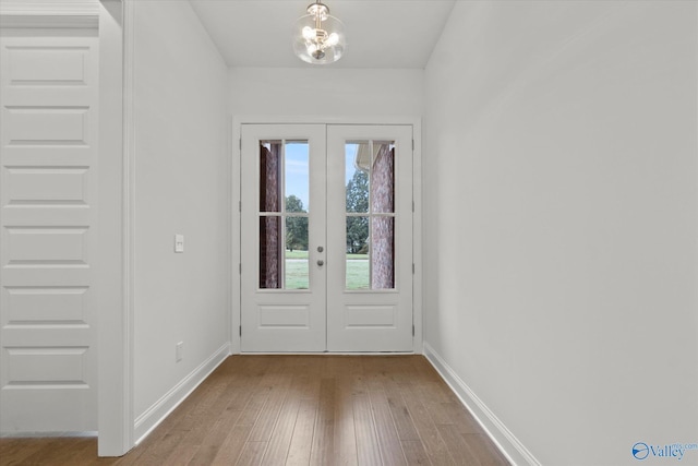 doorway with an inviting chandelier, light hardwood / wood-style floors, and french doors