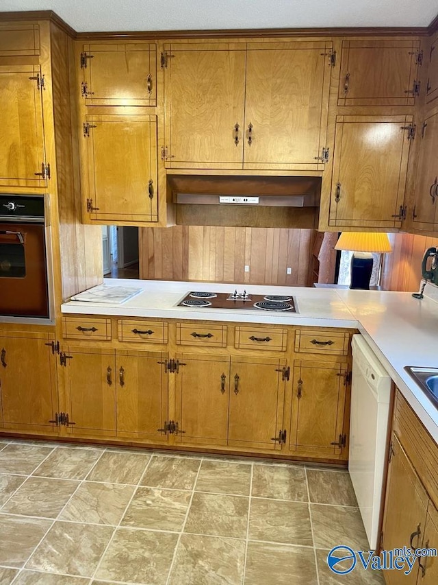 kitchen with brown cabinets, electric cooktop, oven, and white dishwasher