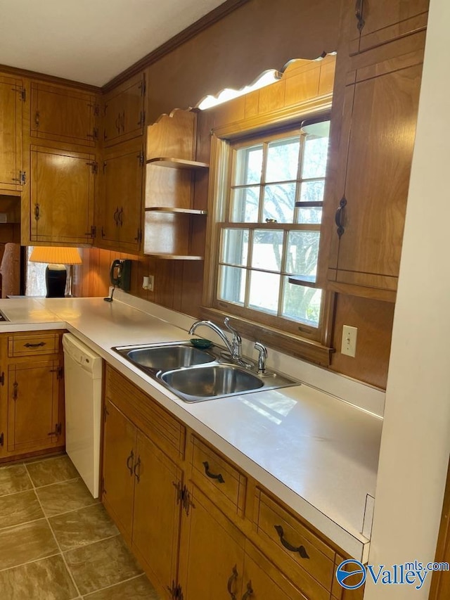 kitchen with white dishwasher, brown cabinetry, a sink, and light countertops