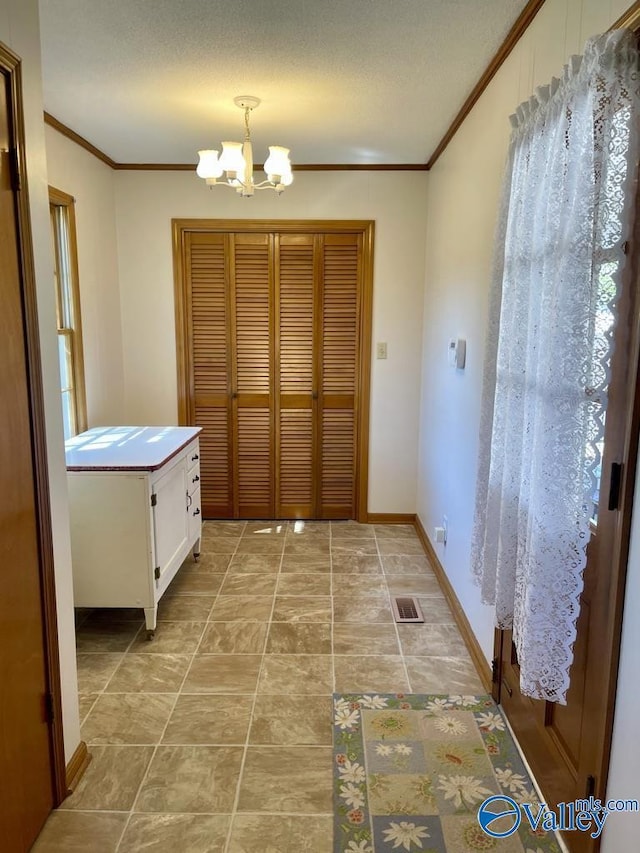 interior space with visible vents, baseboards, ornamental molding, a textured ceiling, and a chandelier