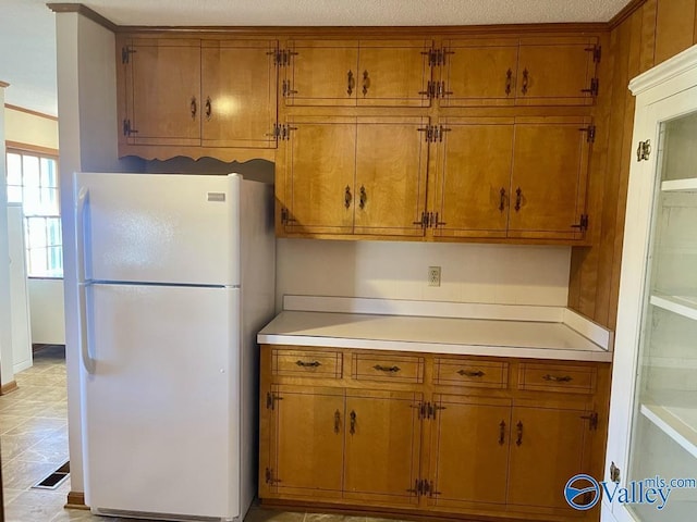 kitchen featuring brown cabinets, visible vents, light countertops, and freestanding refrigerator