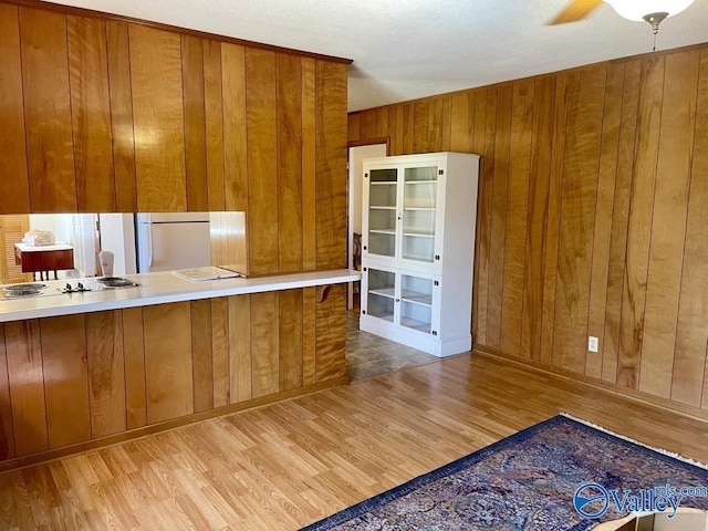 kitchen with wooden walls, brown cabinets, wood finished floors, and refrigerator