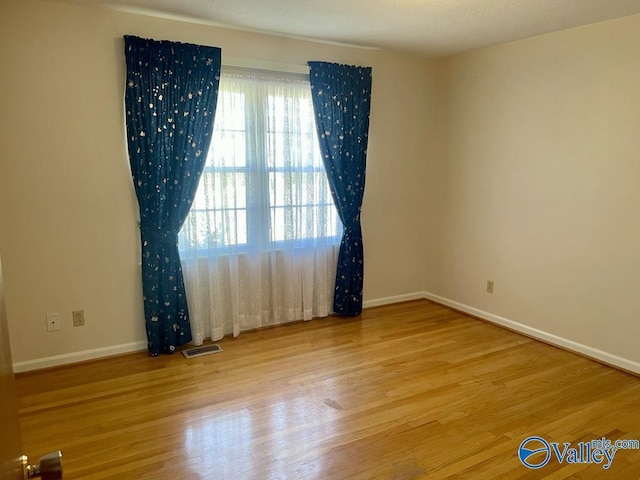 spare room with visible vents, baseboards, and wood finished floors