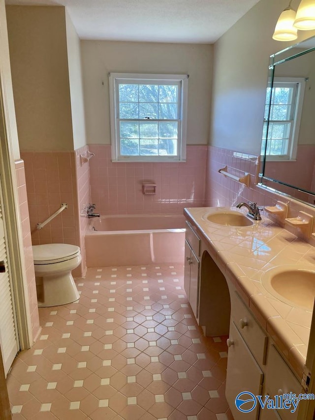 bathroom with a wainscoted wall, a garden tub, a sink, and tile walls