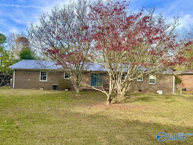 rear view of property featuring brick siding, a lawn, and central AC unit