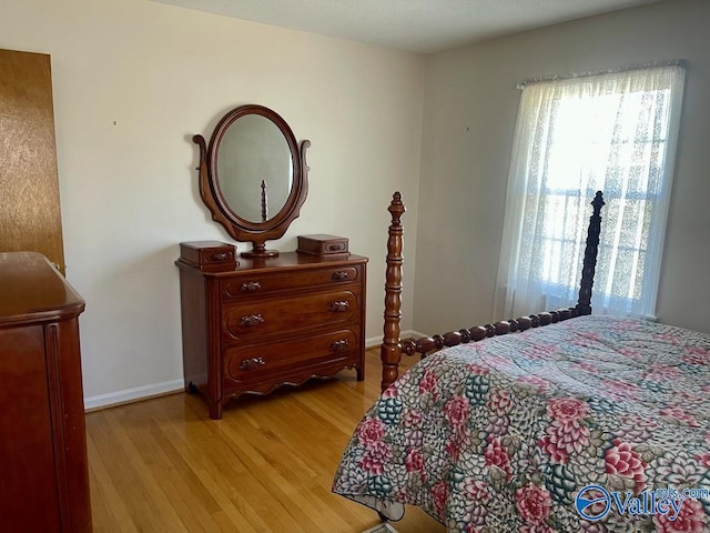 bedroom featuring light wood finished floors and baseboards