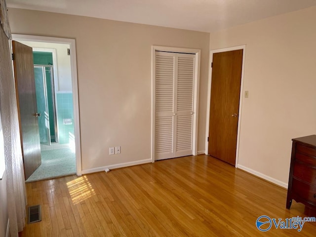 unfurnished bedroom with a closet, baseboards, visible vents, and hardwood / wood-style floors