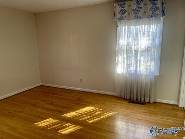 unfurnished room with visible vents, baseboards, and wood finished floors