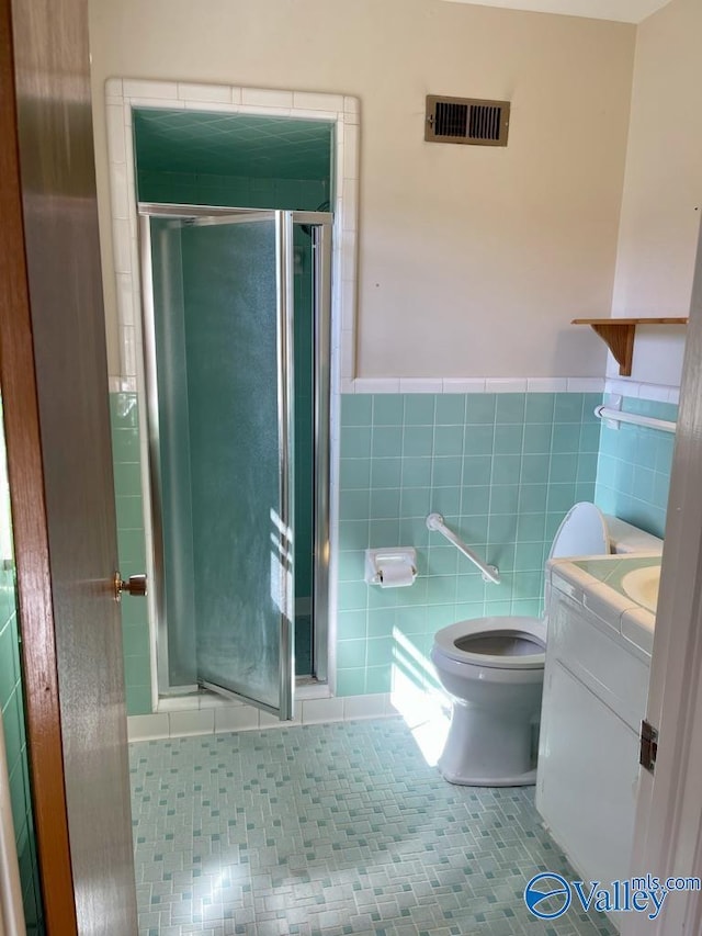 full bath with toilet, a shower stall, visible vents, and tile walls