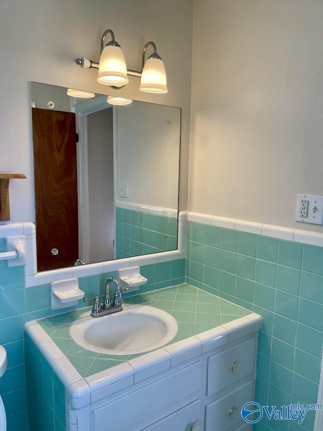 half bath featuring toilet, wainscoting, vanity, and tile walls