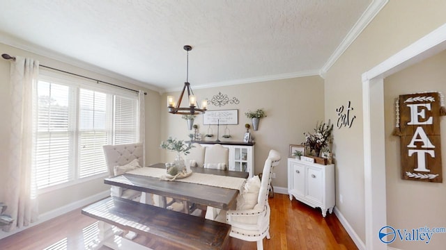 dining room with an inviting chandelier, dark hardwood / wood-style flooring, a textured ceiling, and ornamental molding