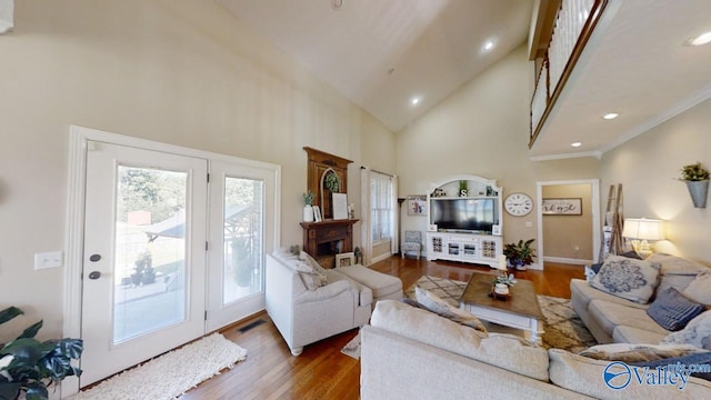 living room featuring high vaulted ceiling, hardwood / wood-style flooring, plenty of natural light, and crown molding