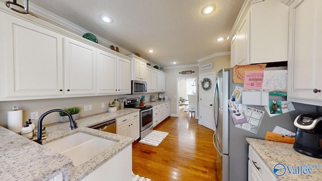 kitchen featuring light wood-type flooring, appliances with stainless steel finishes, white cabinetry, and sink