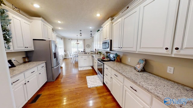 kitchen featuring decorative light fixtures, light stone countertops, stainless steel appliances, white cabinetry, and light wood-type flooring